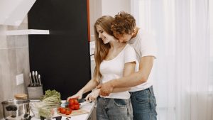 Happy couple preparing a meal together in a bright, modern kitchen, embracing and smiling.