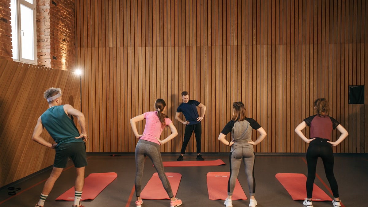People stretching on yoga mats during a fitness class indoors.